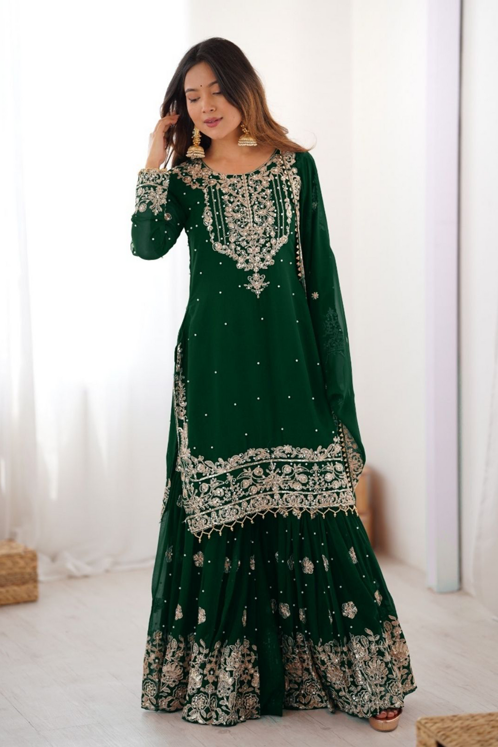 Woman wearing a green embroidered traditional outfit with a white background