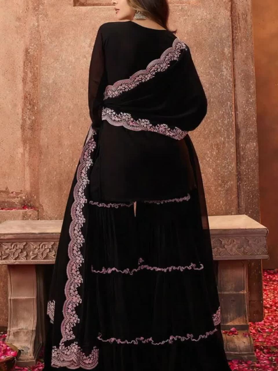 Black dress with intricate white embroidery on a stone wall background