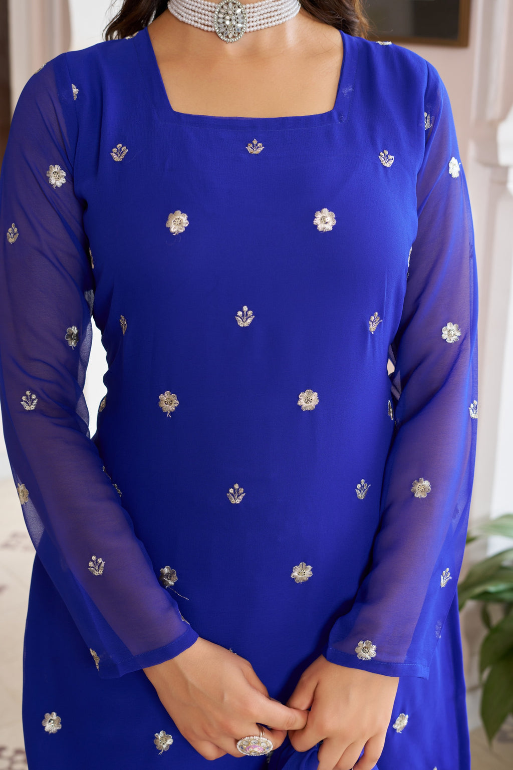 Blue dress with silver floral patterns worn by a person indoors.