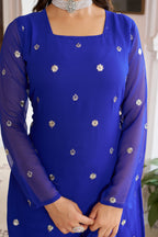 Blue dress with silver floral patterns worn by a person indoors.