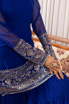 Blue embroidered garment with intricate patterns on a patterned chair.