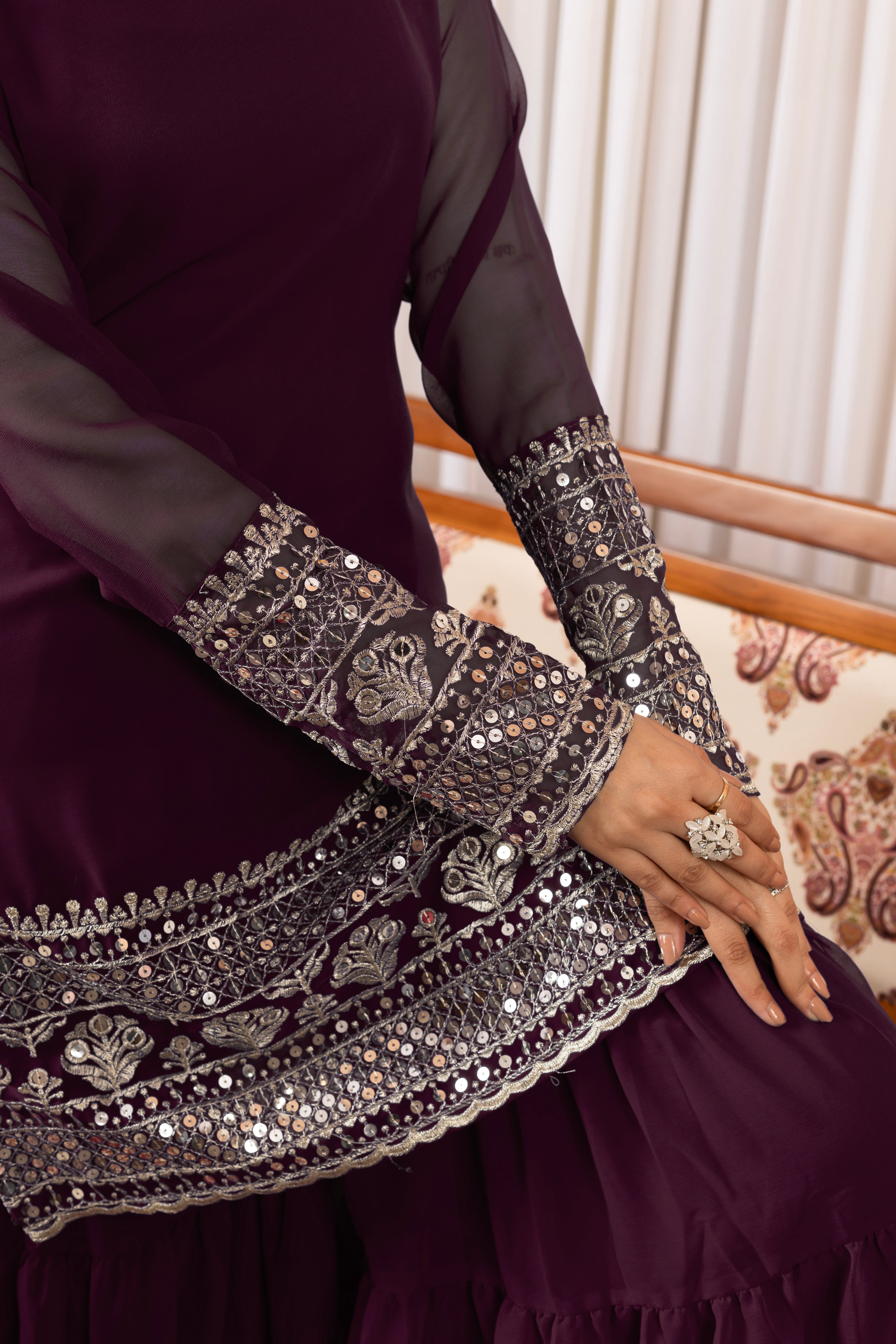 Close-up of a dark purple dress with intricate silver embroidery on a patterned chair.