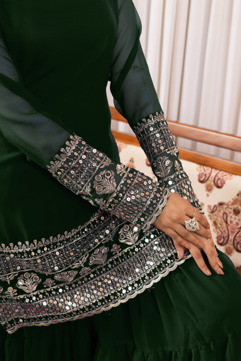 Green traditional outfit with intricate silver embroidery on a patterned chair.