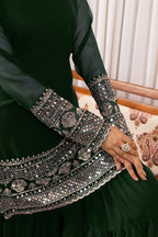 Green traditional outfit with intricate silver embroidery on a patterned chair.