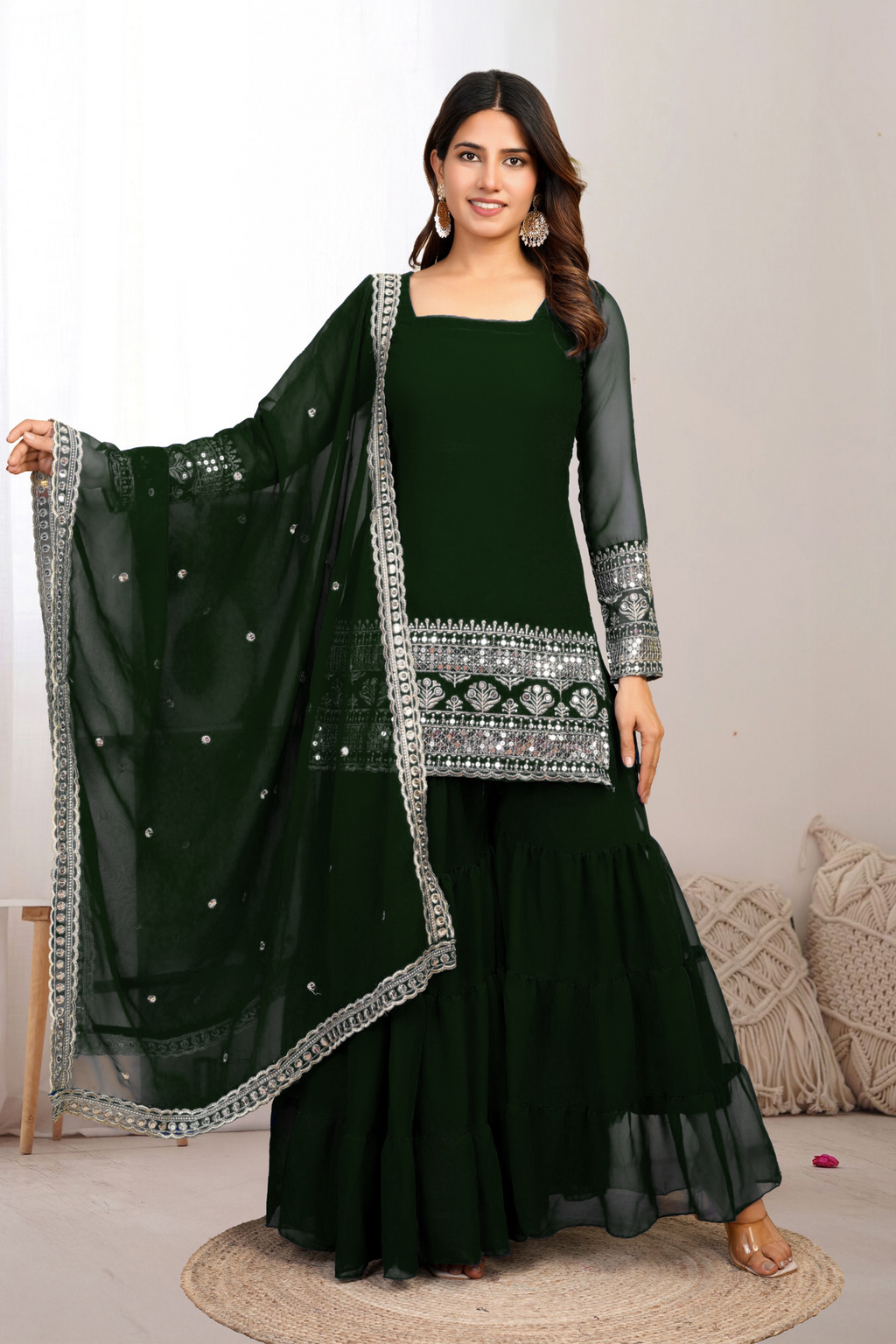 Woman wearing a dark green traditional outfit with a matching dupatta on a neutral background
