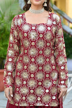 Red embroidered dress with gold patterns worn by a person, with a blurred background.