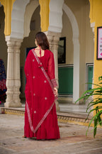 Woman in a red kurti standing in front of a yellow and white architectural structure.