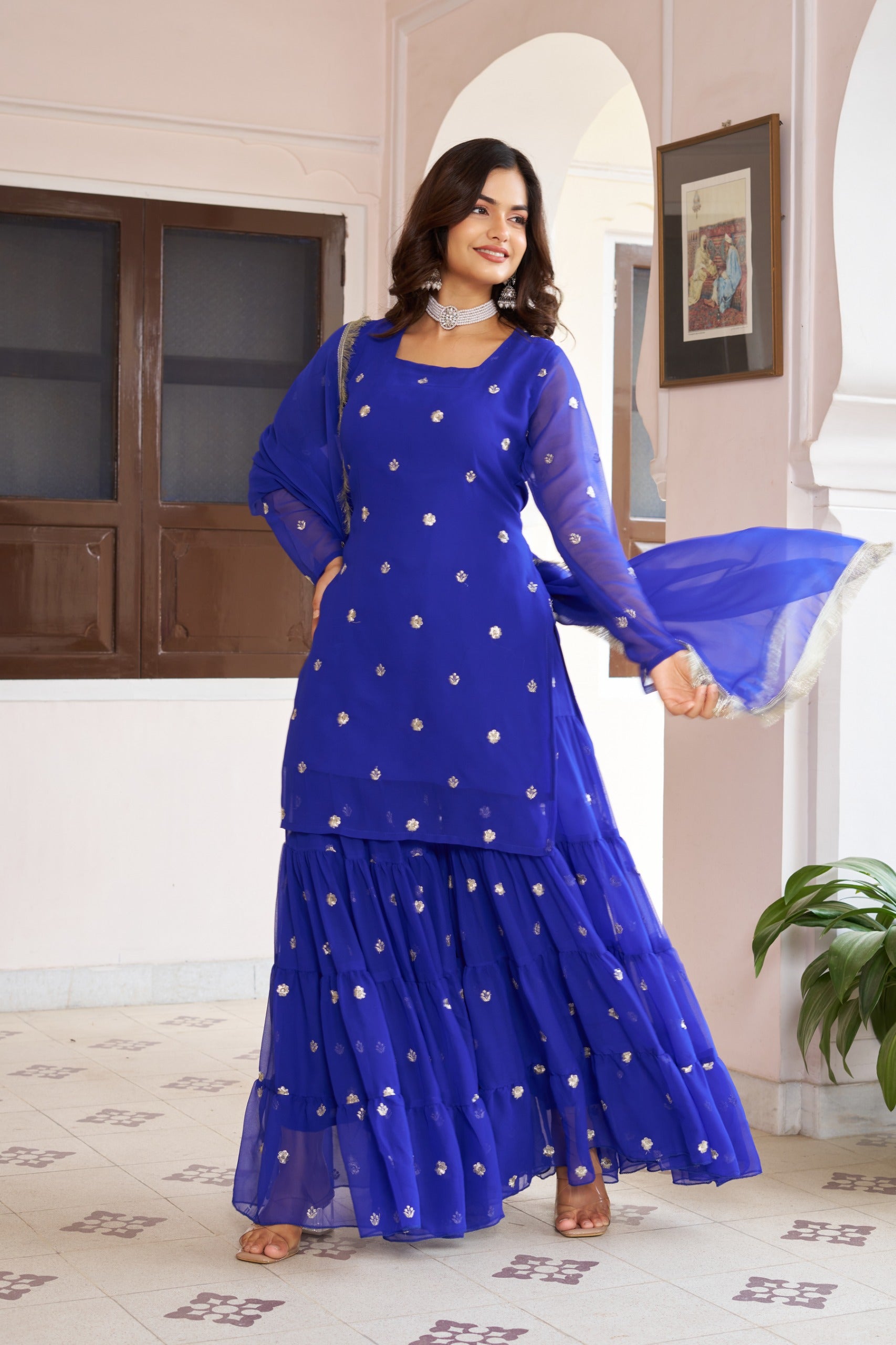 Woman wearing a blue traditional outfit with white polka dots in an indoor setting.