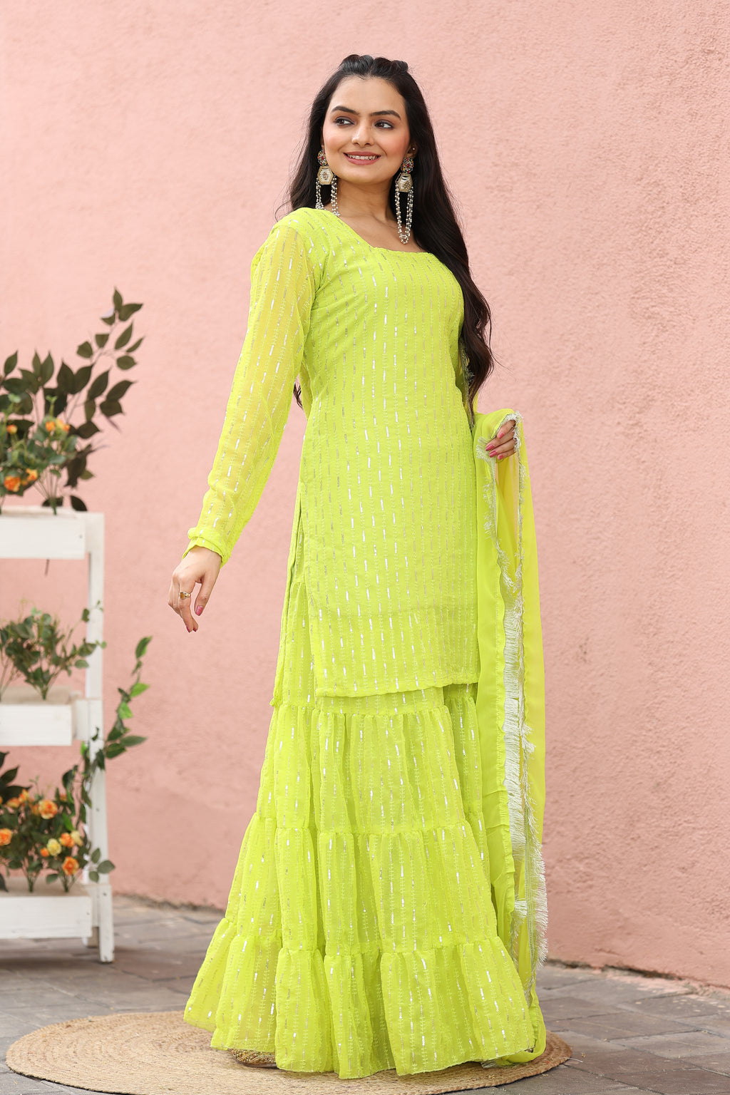 Woman wearing a bright green traditional outfit against a pink background