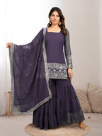 Woman wearing a purple traditional outfit with a matching dupatta on a neutral background