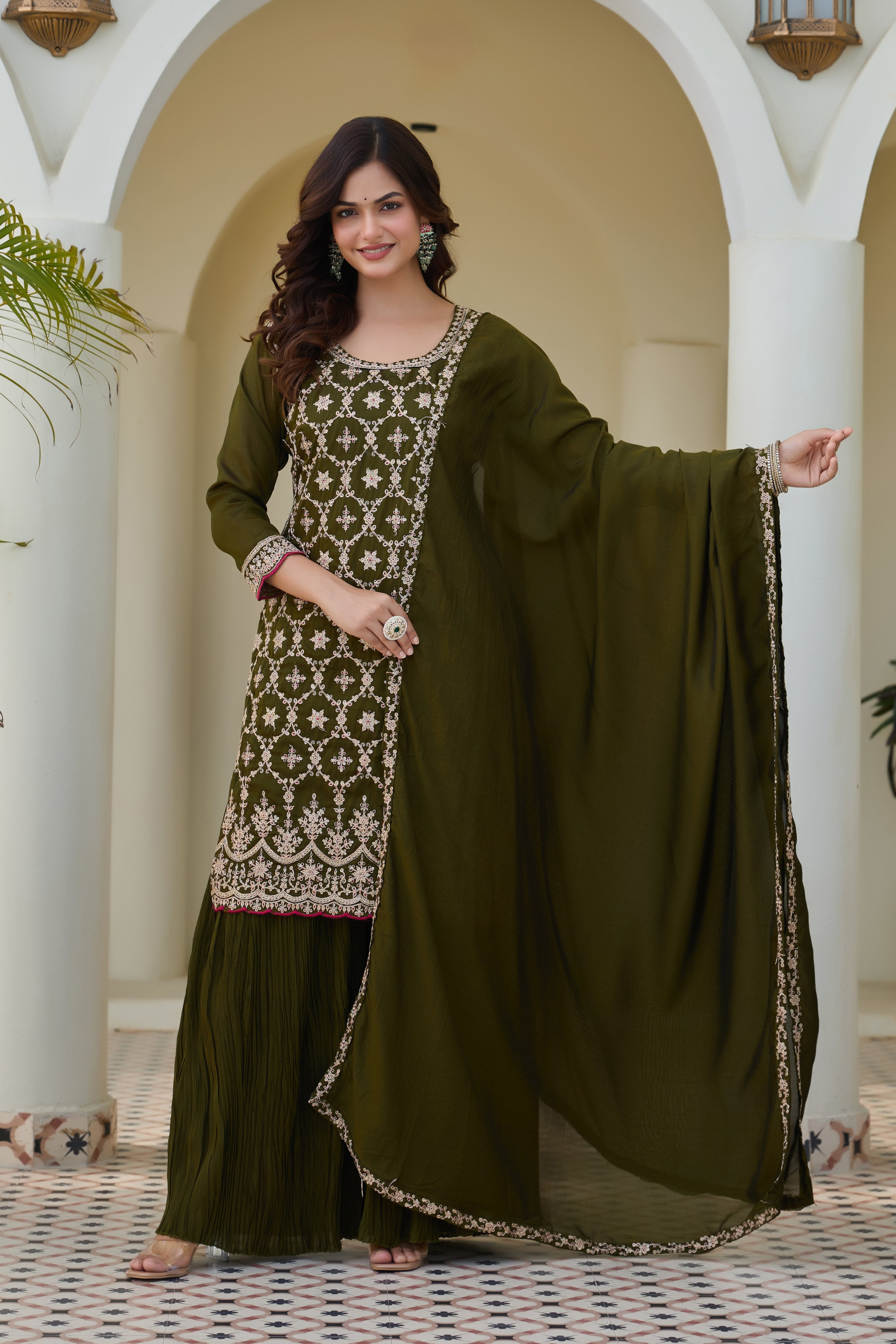 Woman wearing a green traditional outfit with a matching dupatta in an outdoor setting.