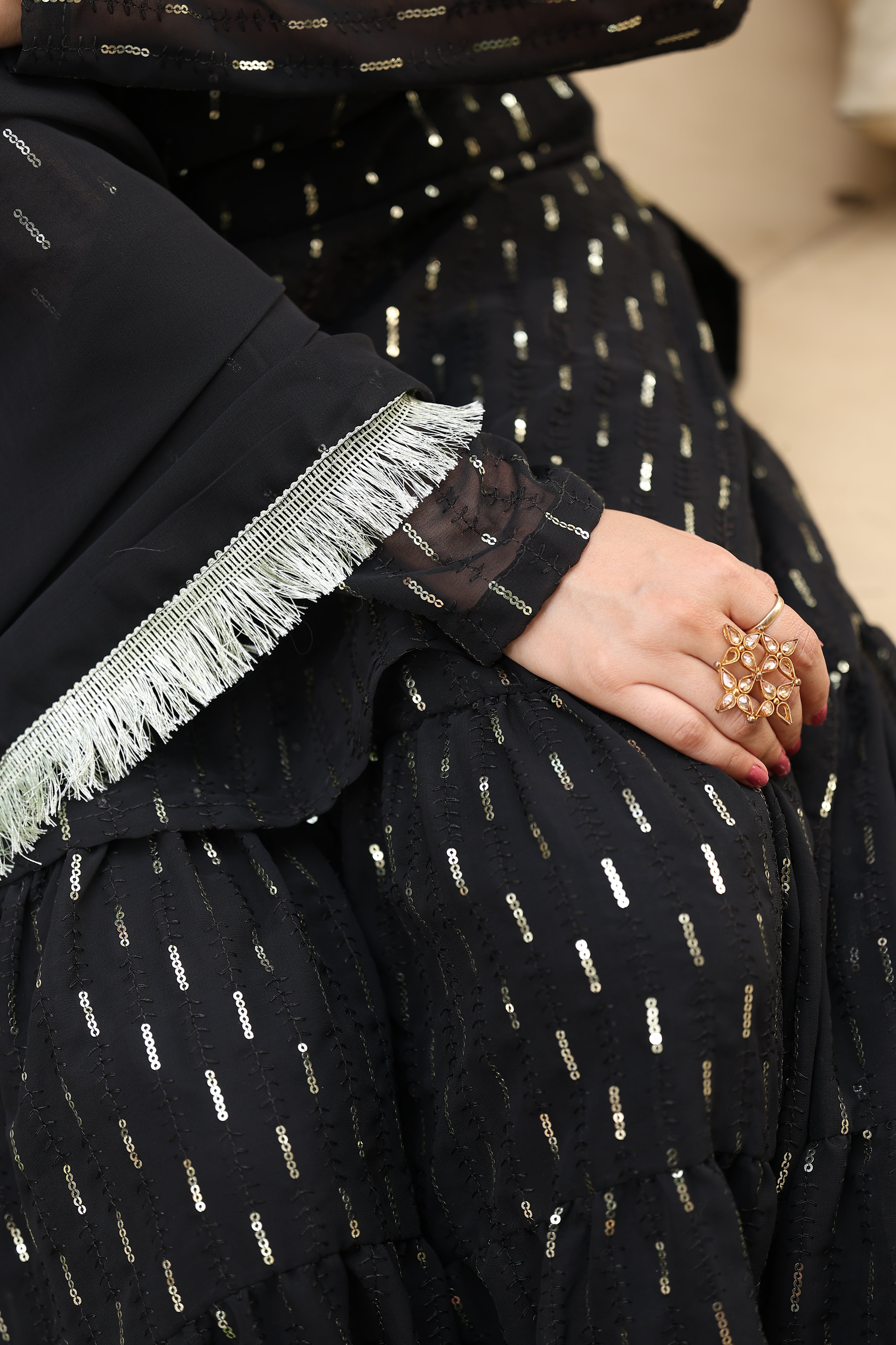 Person wearing a black outfit with gold patterns, holding a small decorative item.