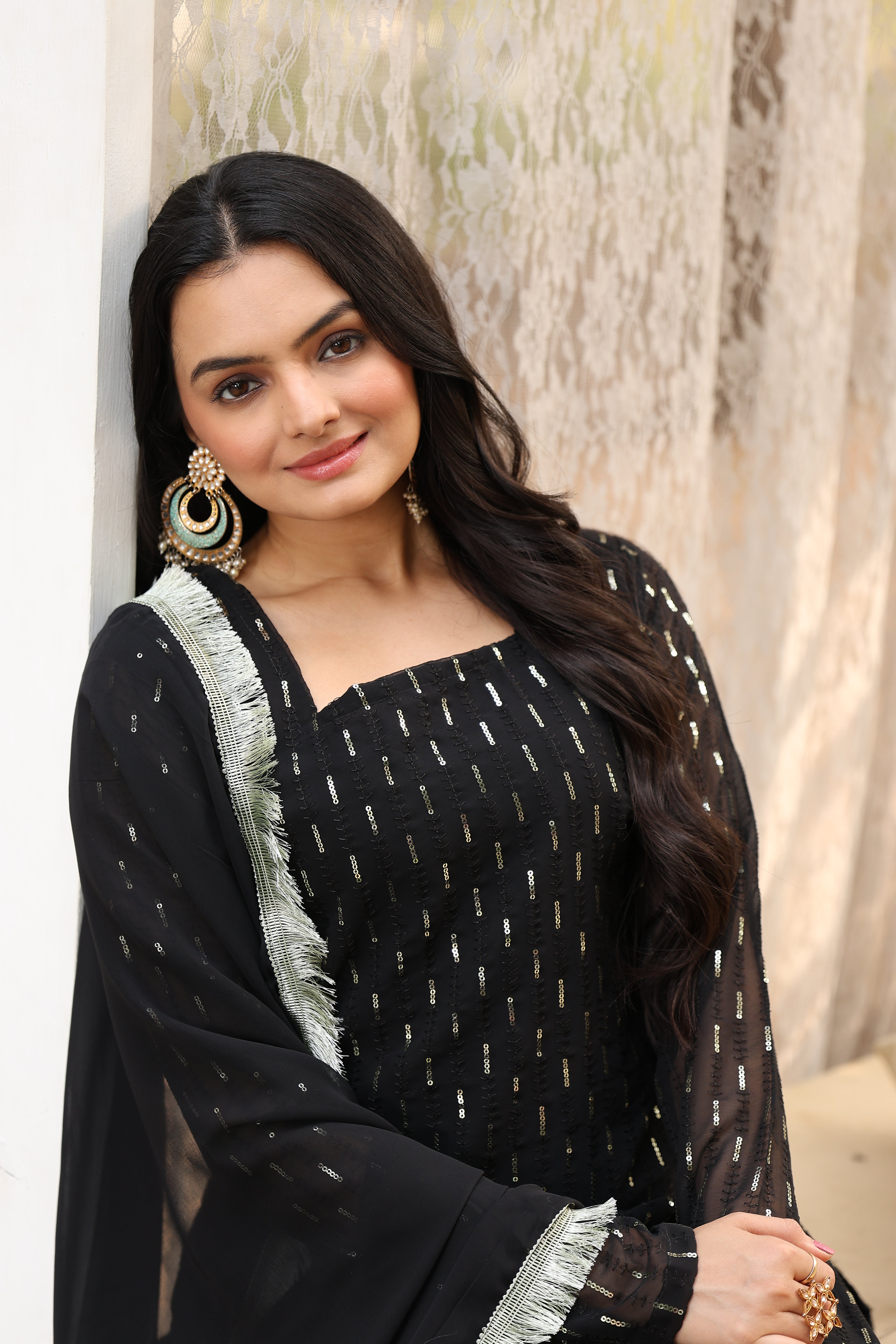 Woman wearing a black traditional outfit with white patterns on a light background