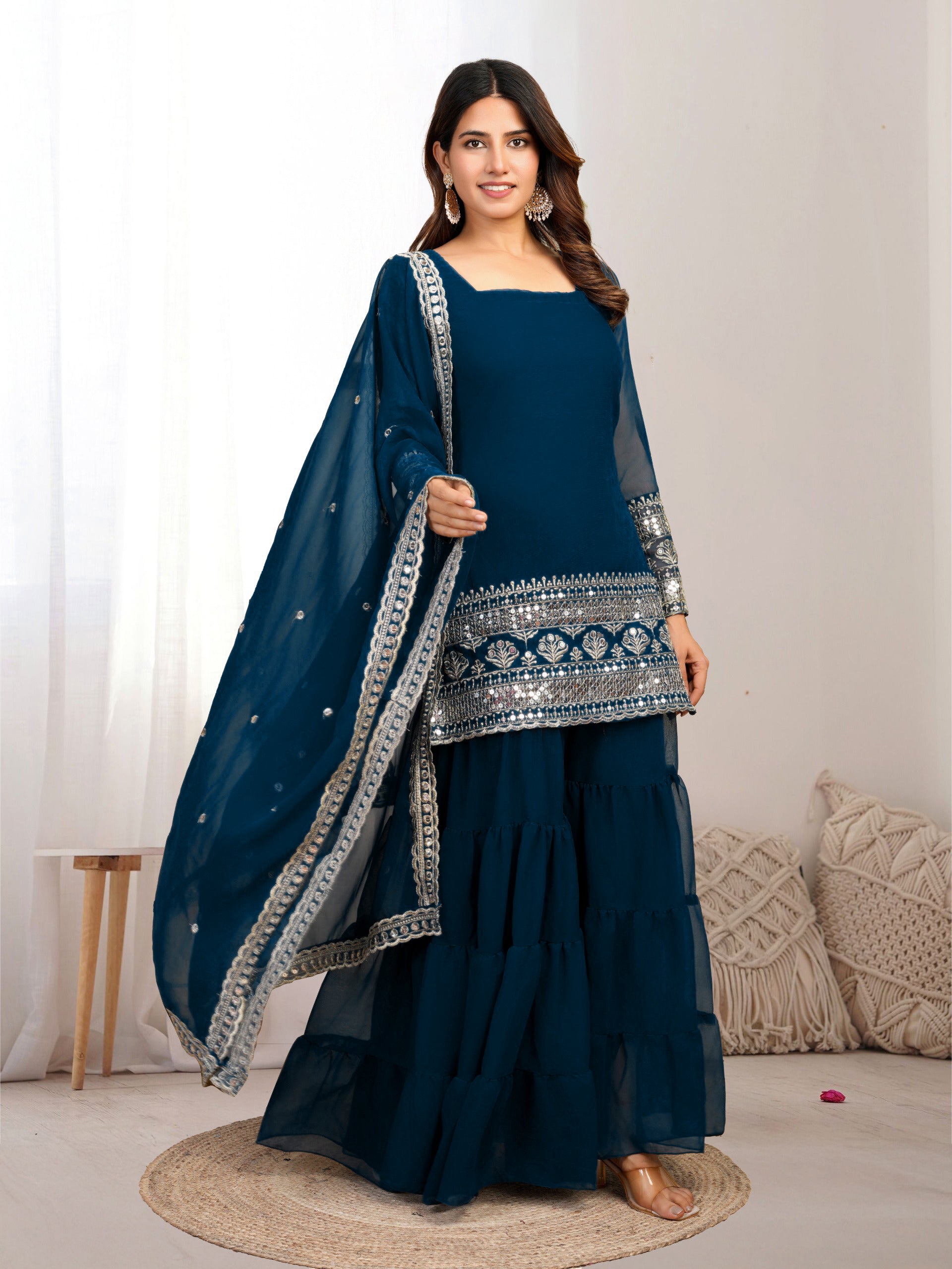 Woman wearing a traditional blue outfit with silver embroidery on a white background