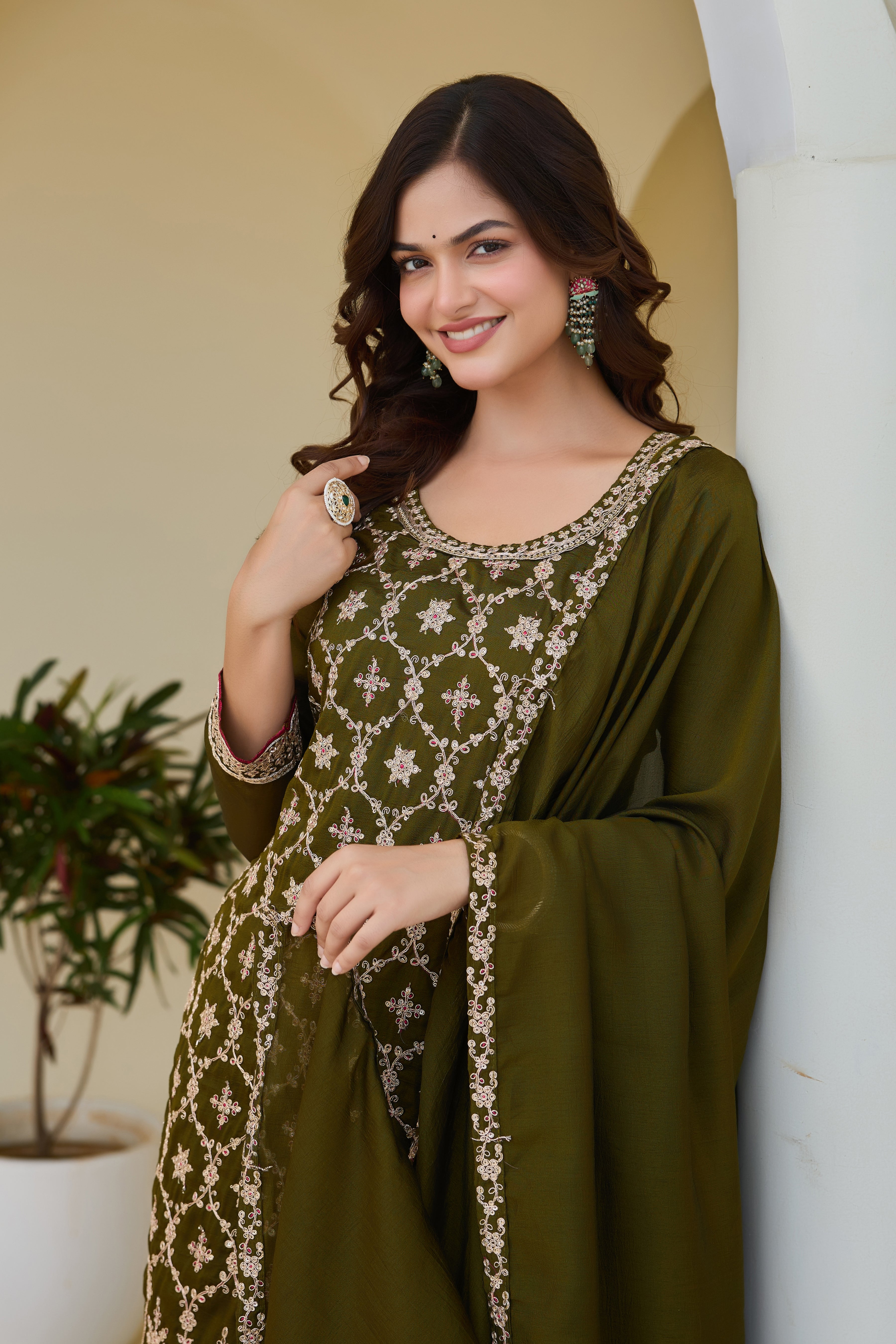 Woman wearing a green traditional outfit with floral patterns indoors.