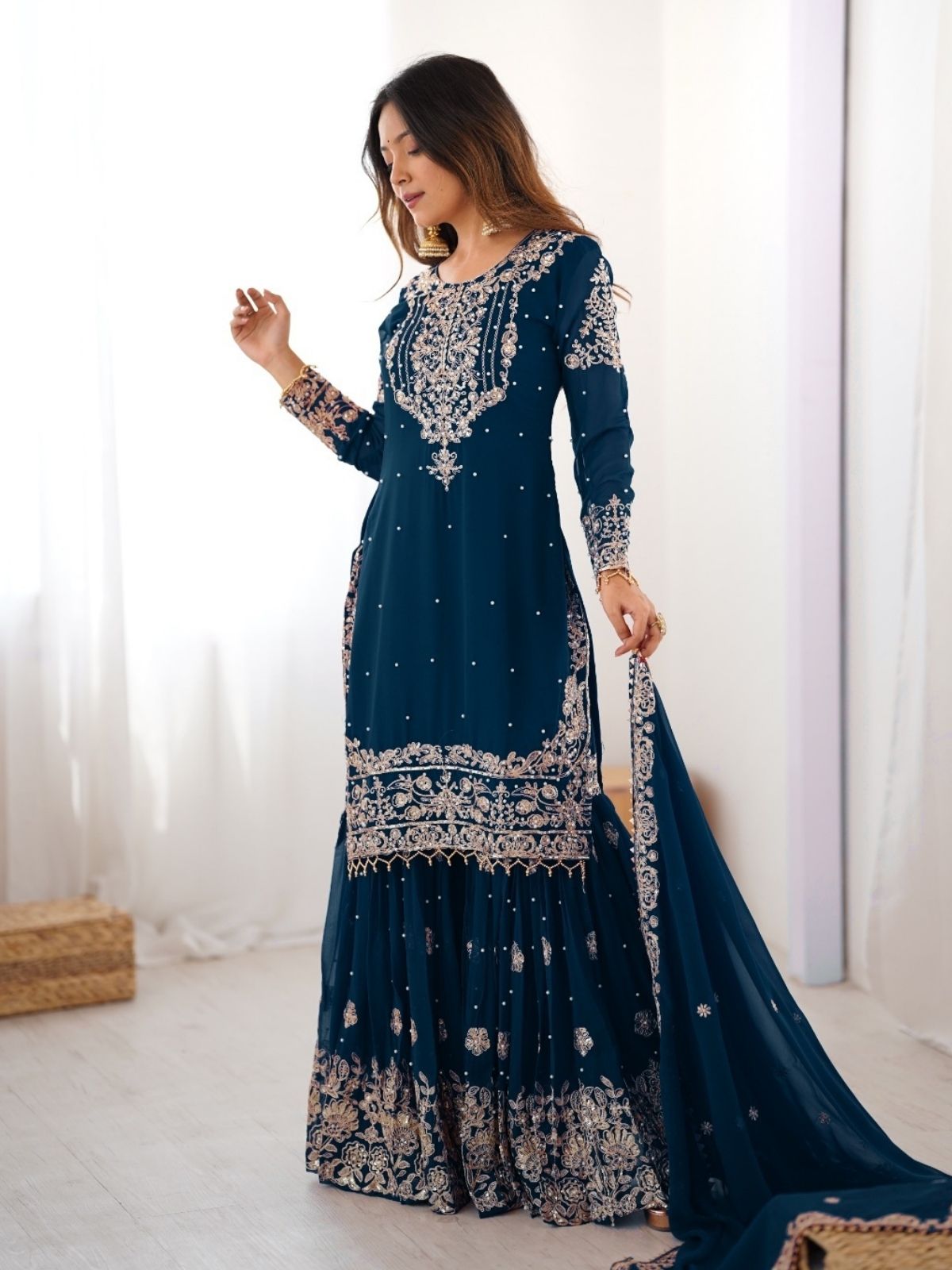 Woman wearing a blue embroidered dress with a white background