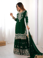 Woman wearing a green embroidered traditional outfit indoors.