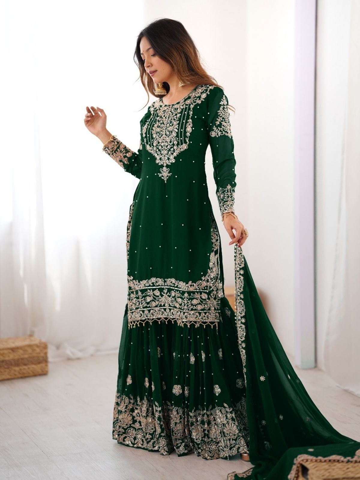 Woman wearing a green embroidered traditional outfit indoors.