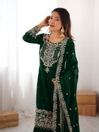 Woman wearing a green embroidered traditional outfit indoors.