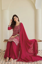 Woman wearing a red and gold traditional outfit with a matching dupatta in an elegant setting.