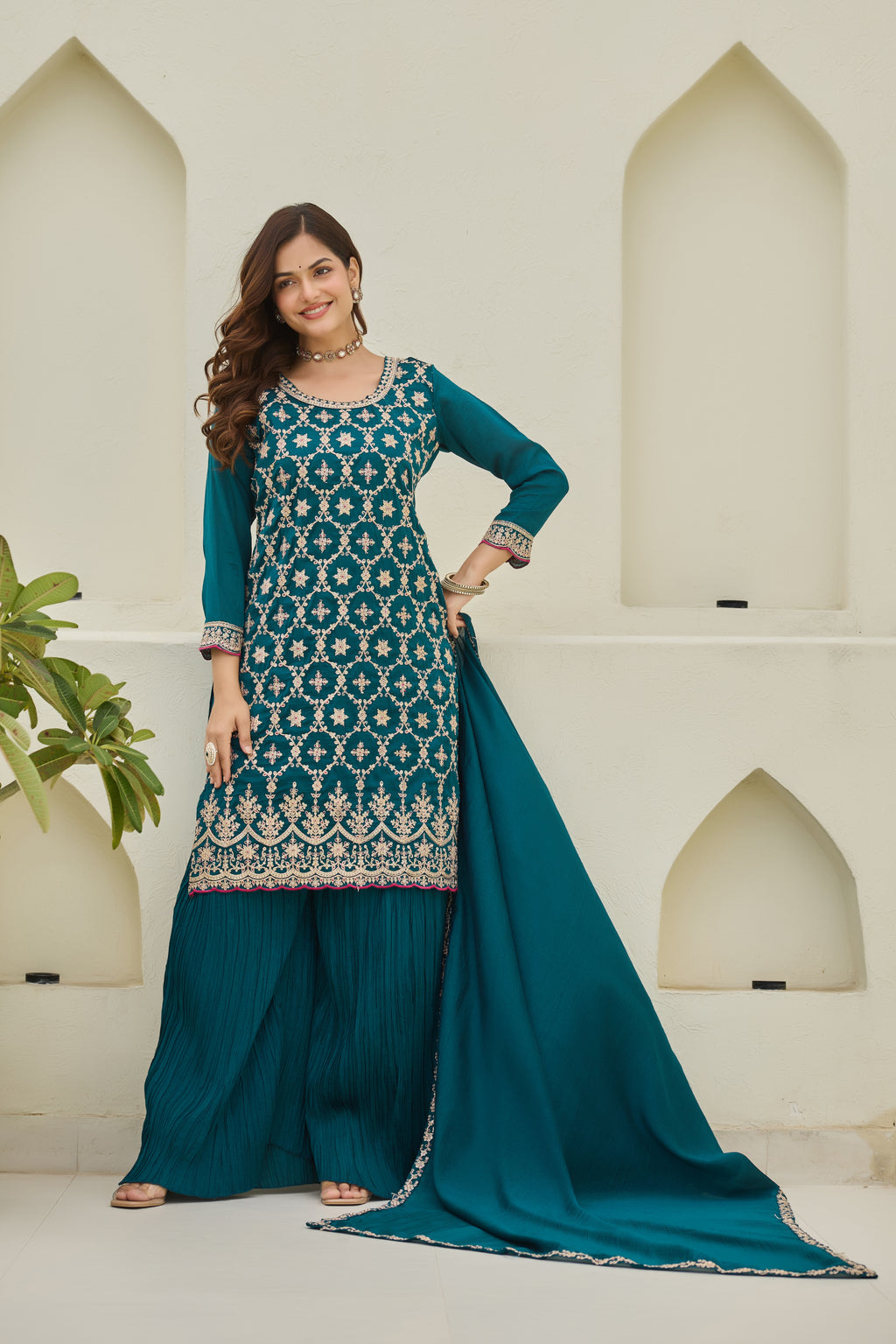 Woman wearing a teal and white traditional outfit with a matching dupatta against a neutral background