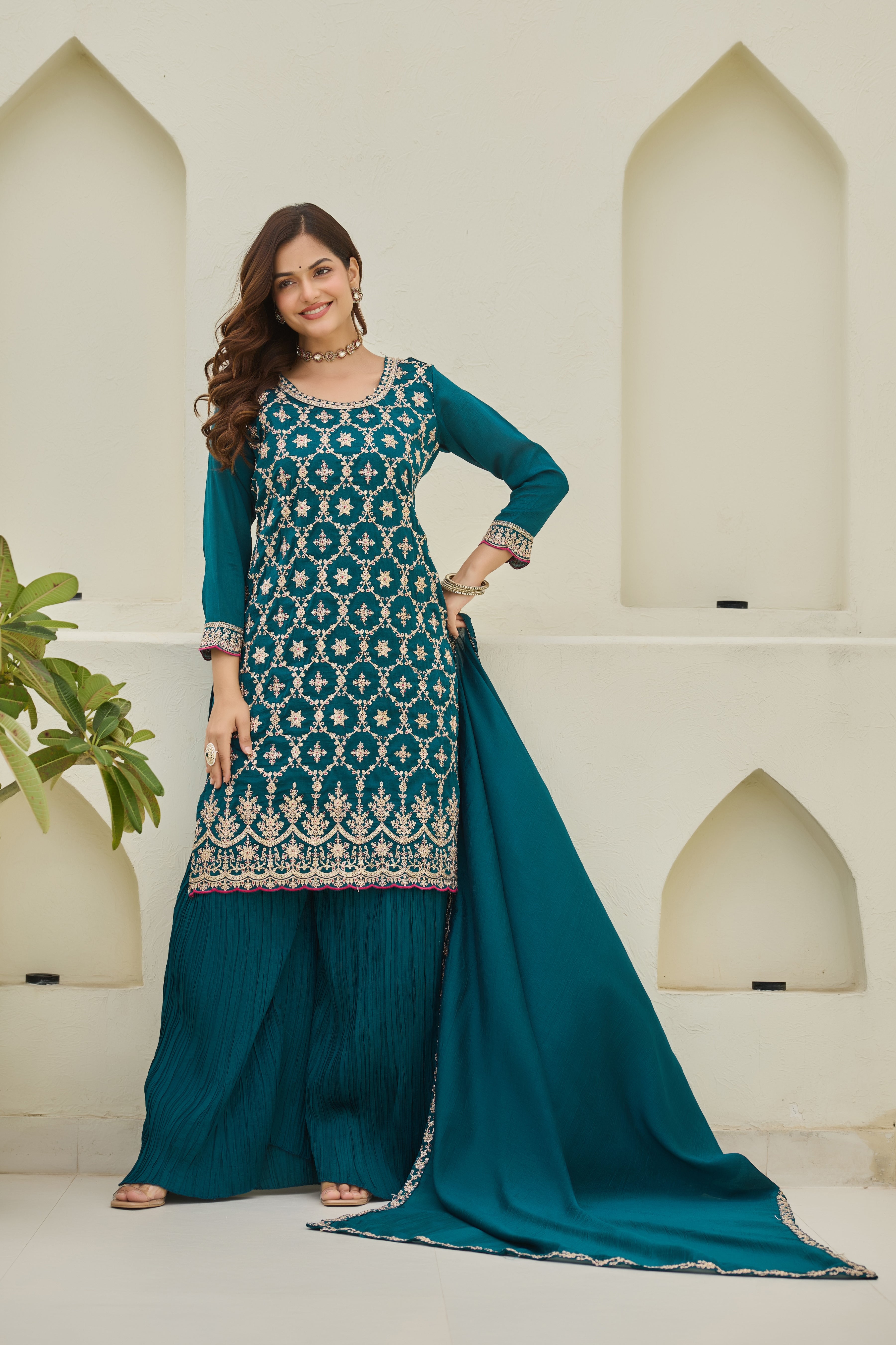 Woman wearing a teal and white traditional outfit with a matching dupatta against a neutral background