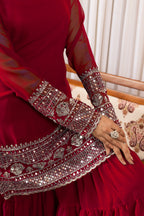 Red traditional outfit with intricate silver embroidery on a patterned chair.