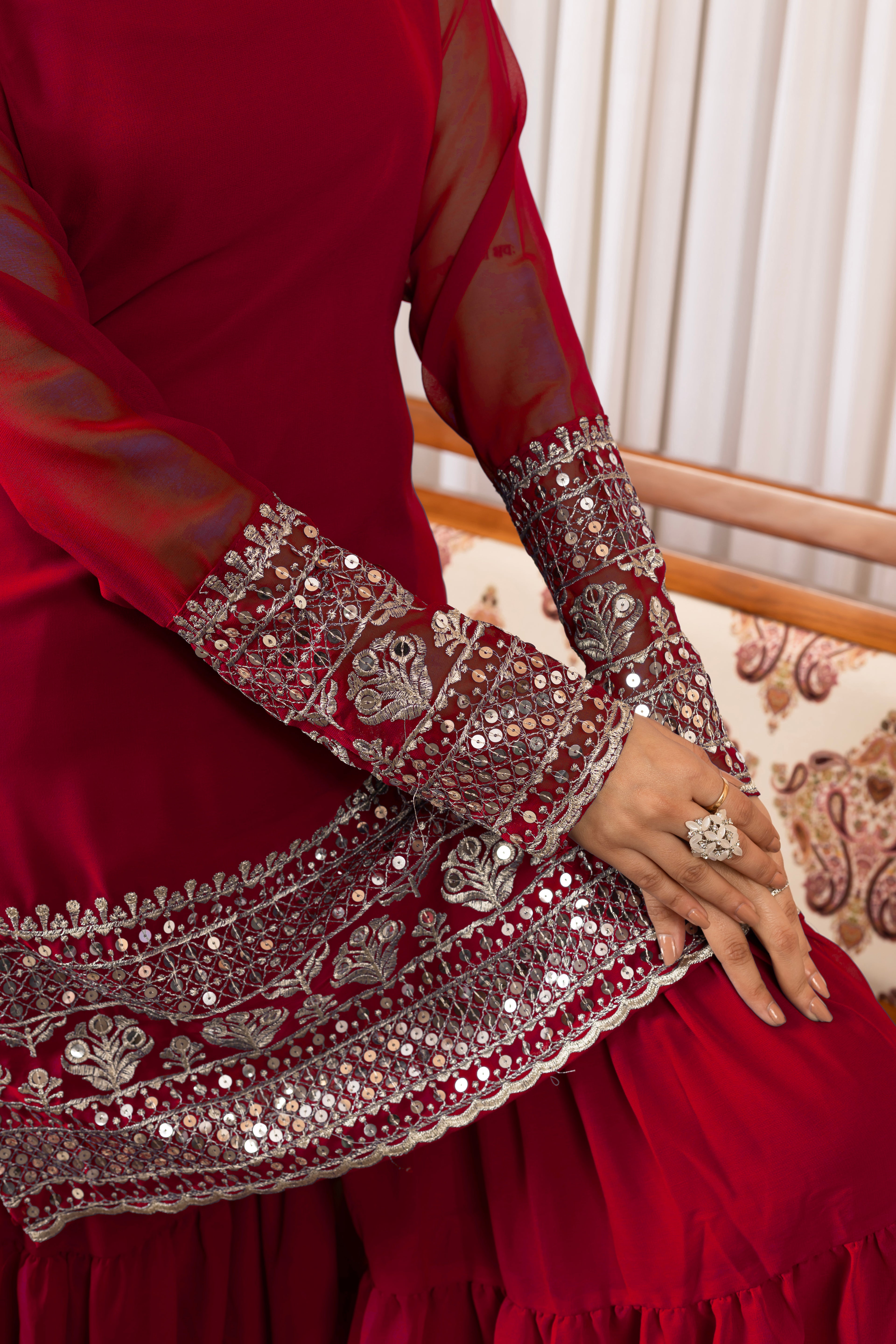 Red traditional outfit with intricate silver embroidery on a patterned chair.