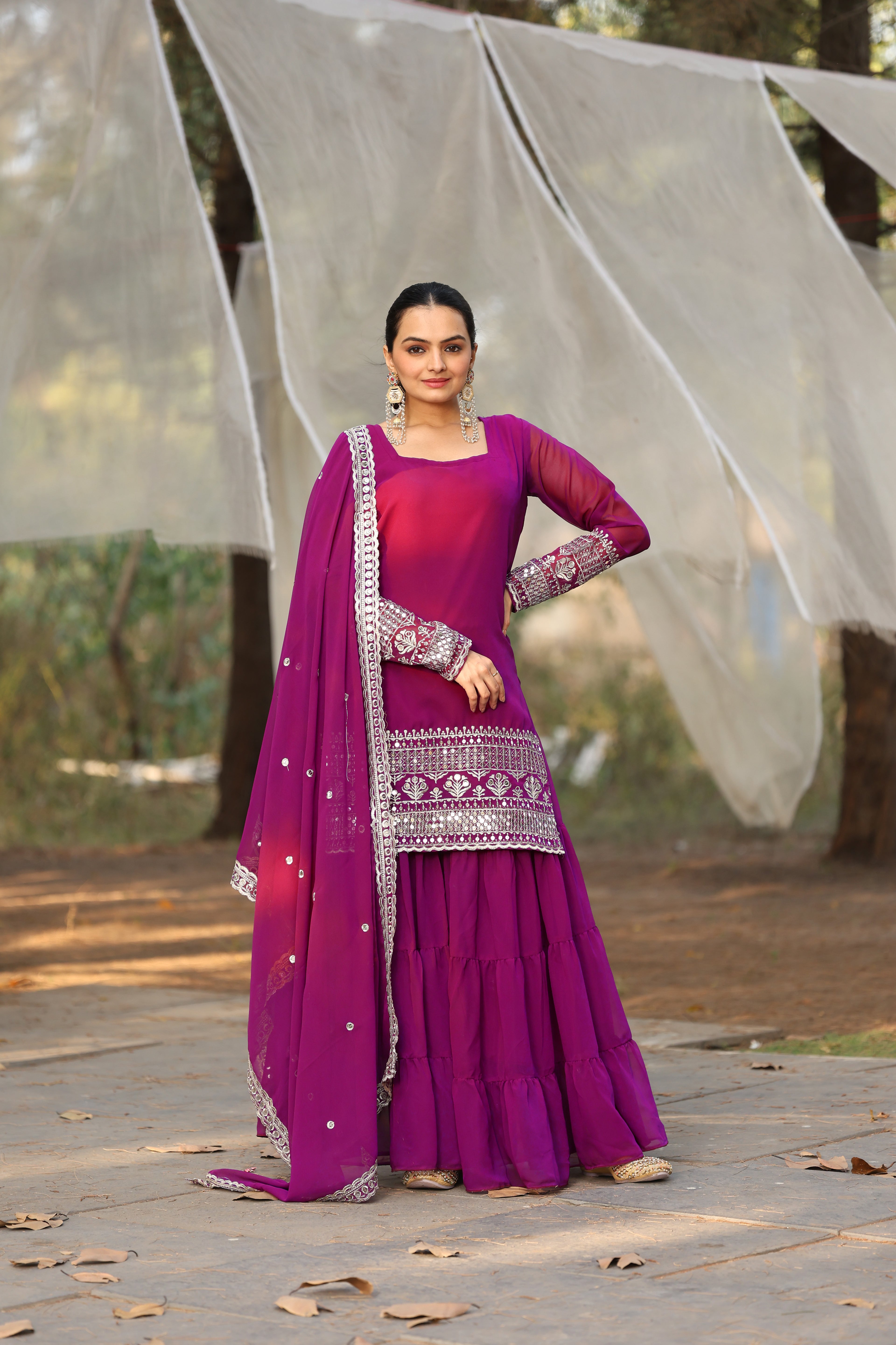 Woman in a traditional pink outfit with a dupatta standing outdoors.