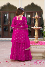 Woman in a pink traditional dress standing in front of a fountain.