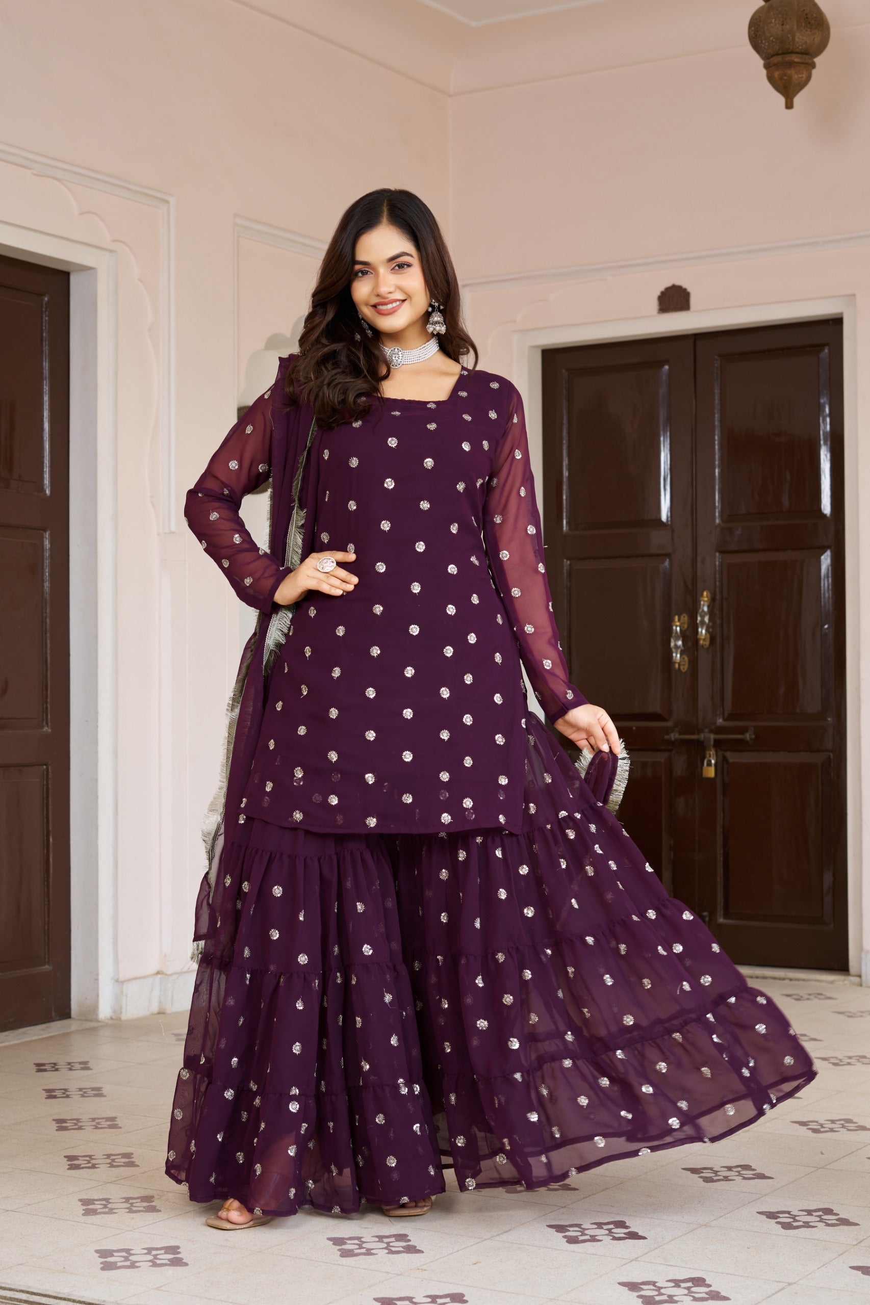 Woman wearing a purple dot dress with a matching dupatta in a room.