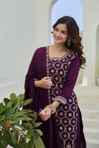 Woman in a purple embroidered outfit standing in a decorative setting