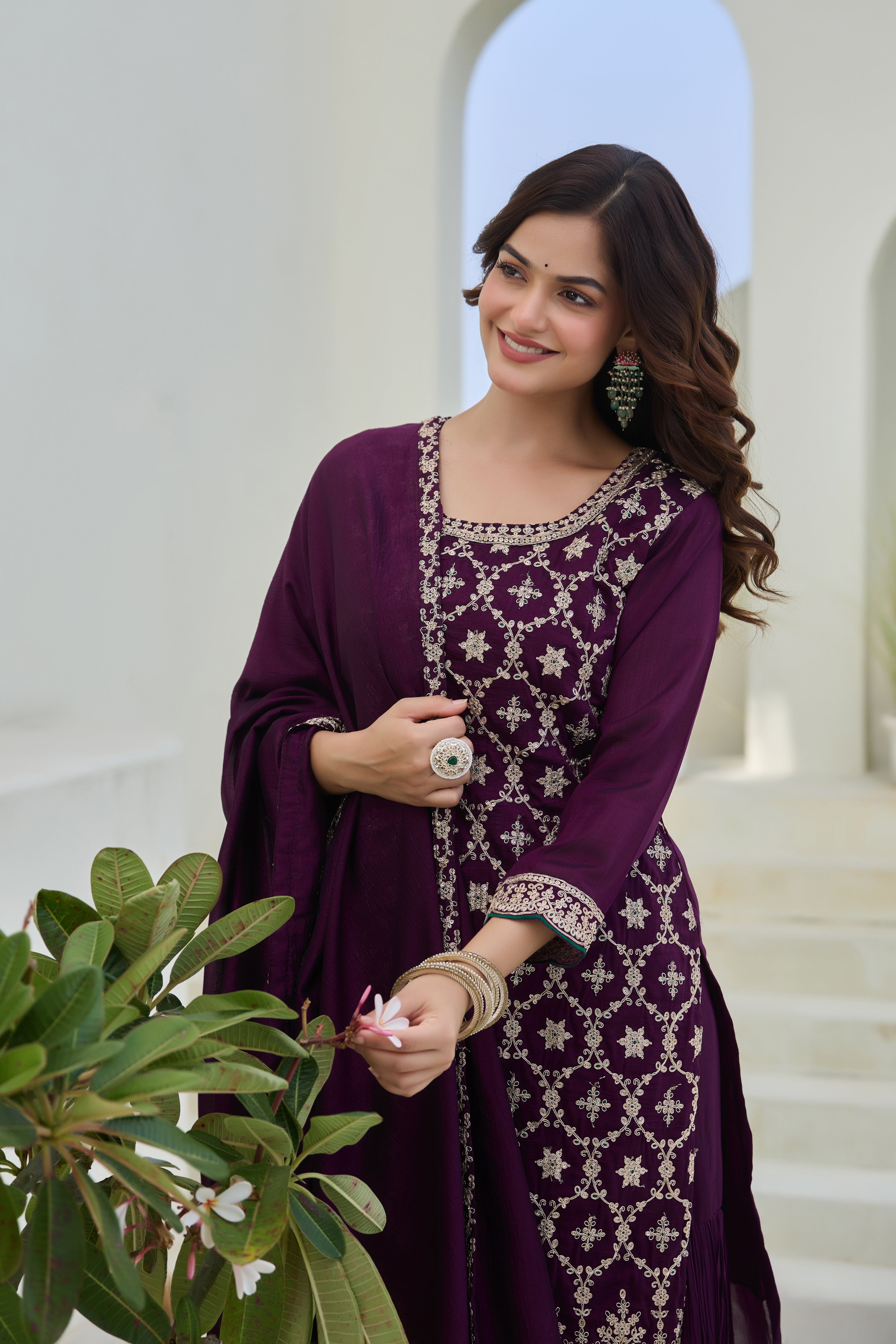 Woman in a purple embroidered outfit standing in a decorative setting