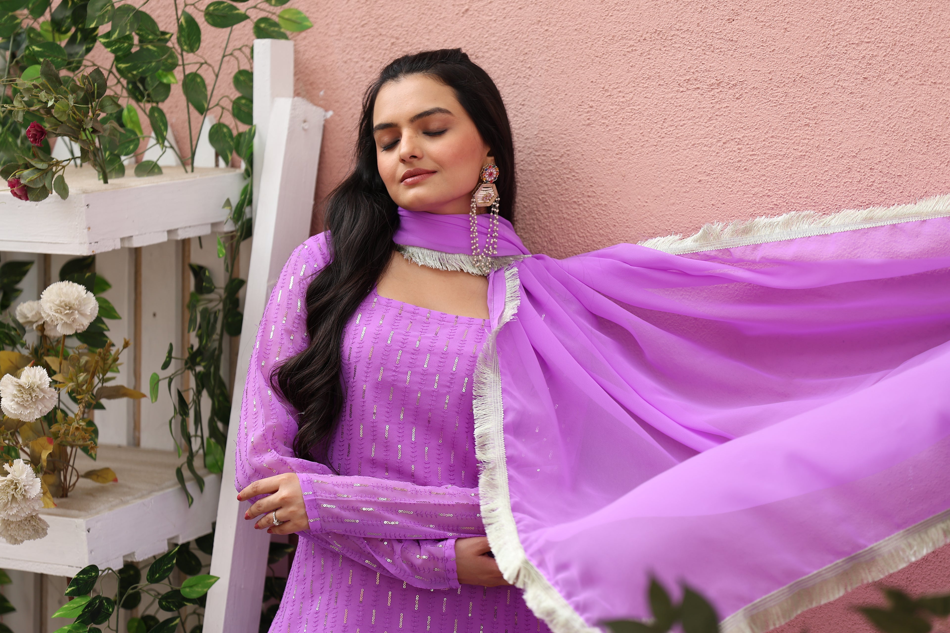 Woman in a purple traditional outfit with a pink background