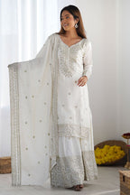 Woman wearing a white traditional outfit with a matching dupatta in a bright setting
