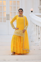 Woman in a yellow traditional outfit standing on a white staircase.